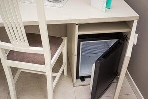 Una kitchenette compacta con refrigerador, una silla y una mesita.