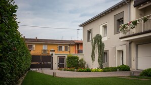 A residential building with a gated entrance, a well-maintained lawn, and a balcony with hanging plants. - Borgocinquanta (Isola della Scala)
