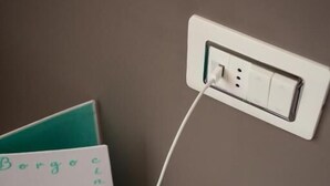A smartphone connected to a power outlet on a wall, with a card next to it. - Borgocinquanta (Isola della Scala)