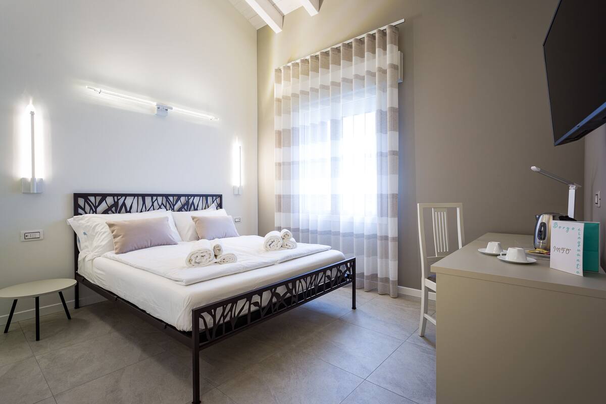 A neatly arranged hotel room with a bed, bedside table, and a small desk area.
