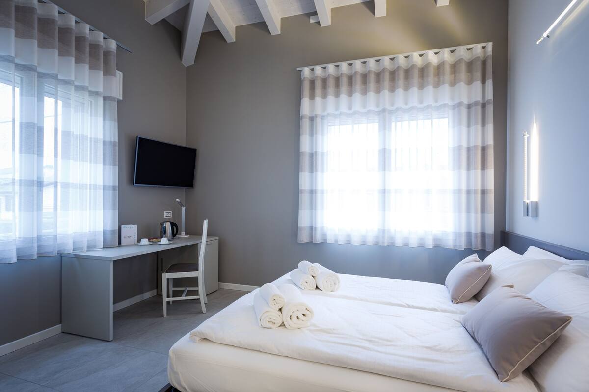 A modern hotel room with a large bed, a desk, and a TV.