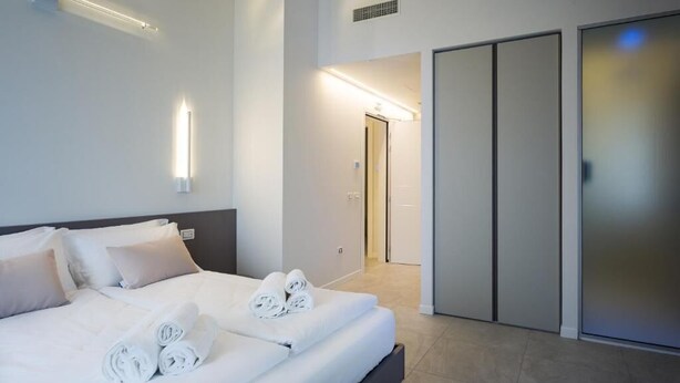 A modern hotel room with a neatly made bed, a walk-in closet, and a bright hallway. - Borgocinquanta (Isola della Scala)
