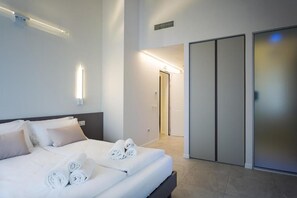 Une chambre d’hôtel moderne avec un lit bien fait, un dressing et un couloir lumineux.