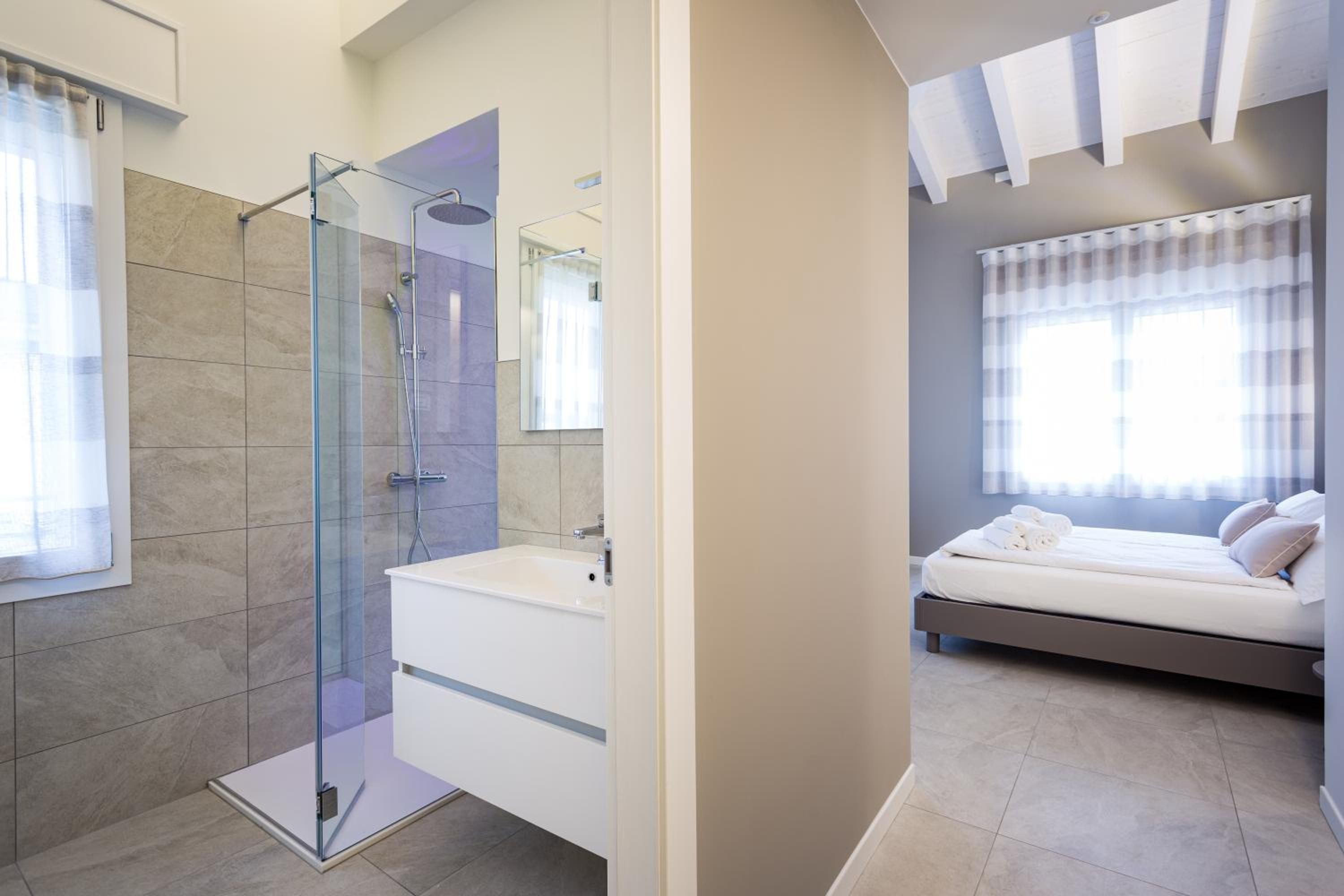 Un baño moderno con cabina de ducha de vidrio, tocador blanco y un espejo grande.