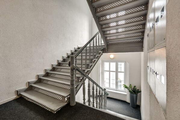 A staircase with a wooden handrail and a carpeted landing.