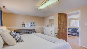 Ein Schlafzimmer mit Bett, Kommode und einer Tür zu einem Wohnbereich.