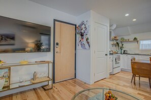 A modern kitchen with white cabinets, a wooden dining table, and a glass coffee table.