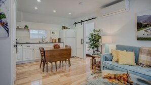 A modern kitchen with white cabinets, a dining table with chairs, and a large window. - 1BR Downtown Urbanitydining, Drink, Cafes & Escape (Colorado Springs)