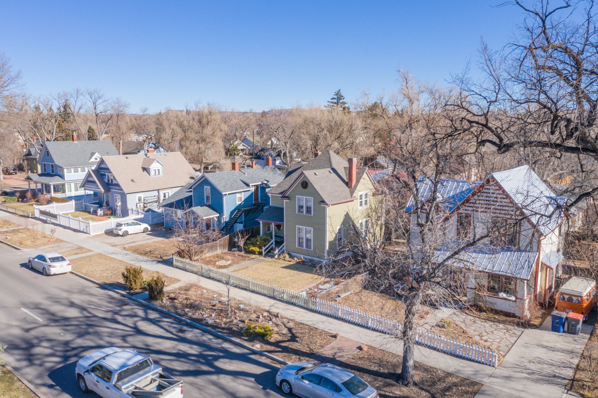 A residential area with houses, a road, and parked cars.