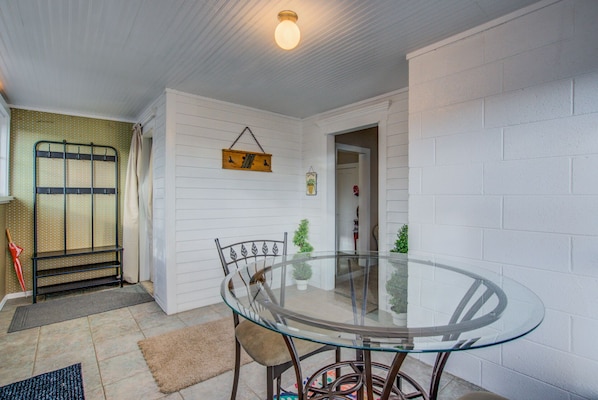 Cozy space with a dining table and chairs, a potted plant, and a metal rack with hooks.