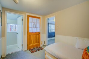 Ein Schlafzimmer mit einem Bett, einer Tür und Blick auf einen blauen Raum durch eine geöffnete Tür.