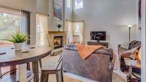 A living room with a fireplace, a TV, a sofa, and a dining area with a table and chairs. - 4BR AF Academyw/hot Tub & Firepit (Colorado Springs)