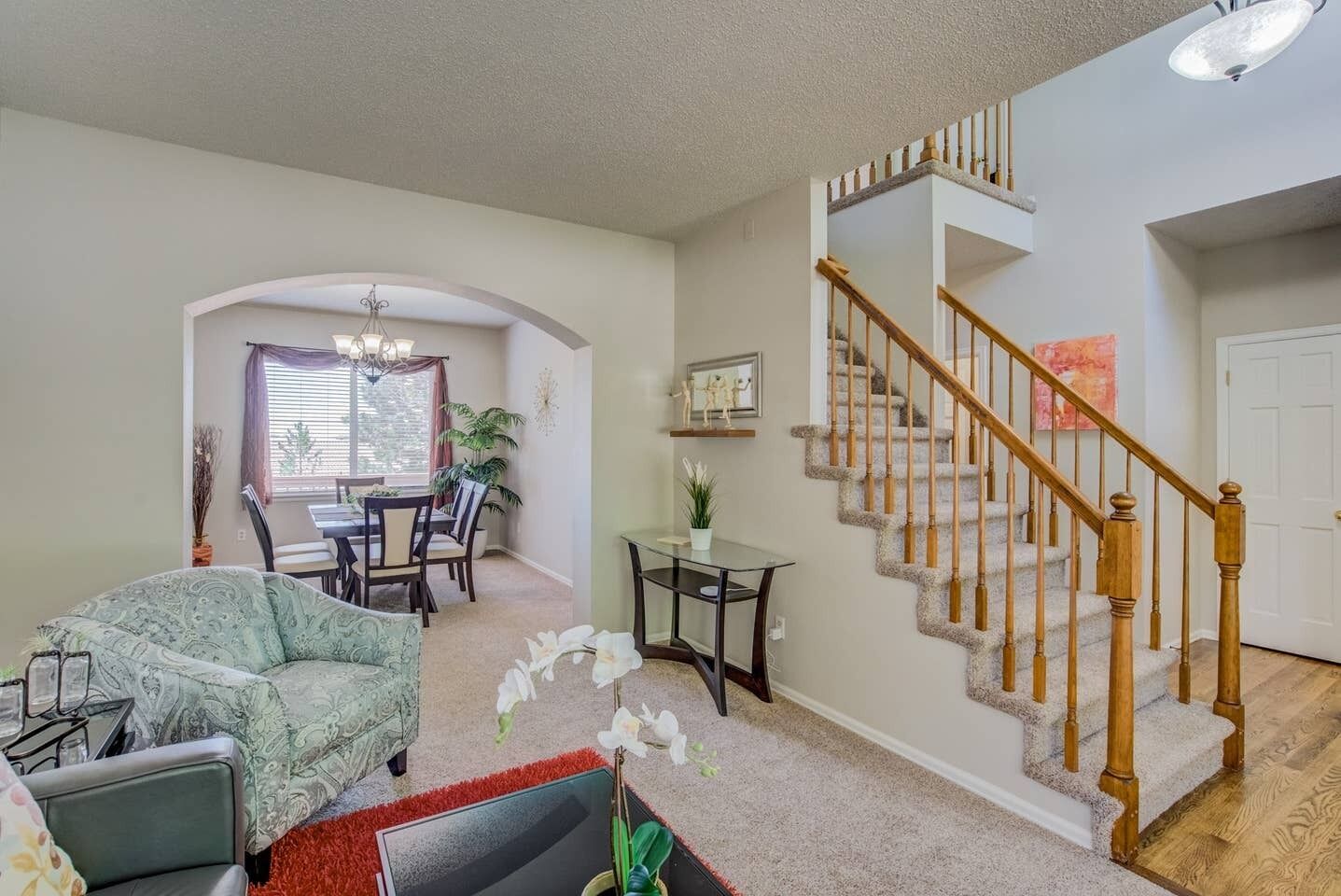 A spacious living room with a dining area, a staircase, and a view of the backyard.