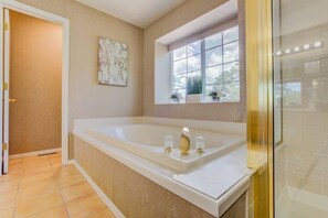 Ein Badezimmer mit einer großen Badewanne, einem Fenster mit Blick und einer Tür zu einem anderen Raum.