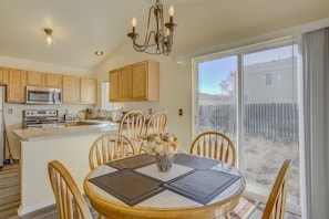 A kitchen with wooden cabinets, a microwave, and a stove. There is a dining table with chairs and a vase of flowers. - South Side COS & Ft. Carson Value Stay! Dogs OK! (Colorado Springs)