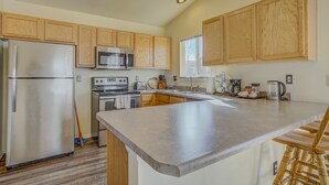 A kitchen with wooden cabinets, stainless steel appliances, a large island, and a window providing natural light. - South Side COS & Ft. Carson Value Stay! Dogs OK! (Colorado Springs)