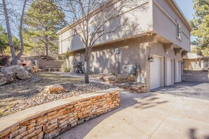 A two-story house with a garage, stone retaining wall, and a barbecue grill in the yard. - Verdant Oasisluxury, Traveler's Home W/hottub! (Colorado Springs)