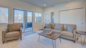 A spacious living room with a sofa, armchair, and coffee table. - Modern Rooftop Patio New-build Townhome in COS (Colorado Springs)