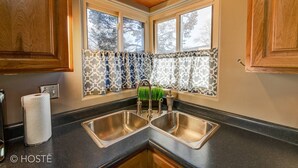 A kitchen with two stainless steel sinks, wooden cabinets, and patterned window treatments. - 3bdmid-century Modernhot Tub, Grill, Close to DT (Colorado Springs)