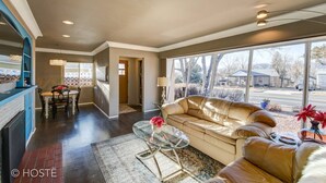 A spacious living room with a large window, a sofa, a glass coffee table, and a fireplace. - 3bdmid-century Modernhot Tub, Grill, Close to DT (Colorado Springs)