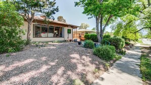 A house with a gravel driveway, a covered porch, and a well-maintained garden. - 3bdmid-century Modernhot Tub, Grill, Close to DT (Colorado Springs)