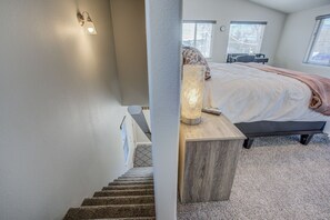 Ein Schlafzimmer mit einem Bett, einem Nachttisch, einer Lampe und einem Fenster.
