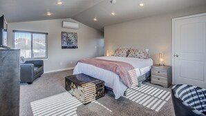 Una camera da letto con un letto, comodini, una cassettiera, una valigia e una sedia.