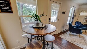 Une table de salle à manger ronde en bois, agrémentée d’un pot de plante, de deux tabourets et d’un sous-verre décoratif.