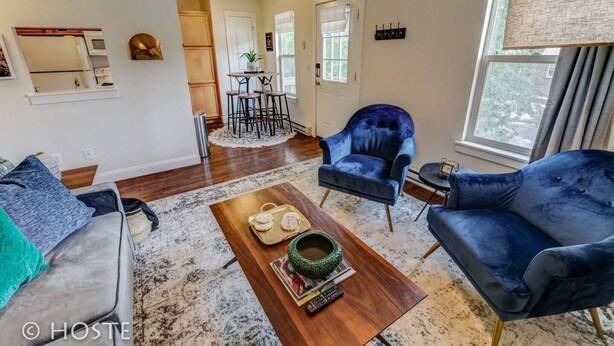 Un salon moderne comprenant un canapé, deux fauteuils, une table basse et un coin repas avec une table et des chaises.