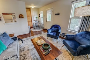 Una sala de estar moderna con un sofá, dos sillones, una mesa de centro y un comedor con una mesa y sillas.