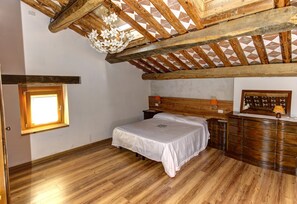 Une chambre avec un plafond en bois, un lit, une commode et une fenêtre.
