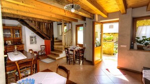 Un amplio comedor con una mesa y sillas de madera, una escalera que lleva a un nivel superior y vistas al jardín a través de un umbral abierto.
