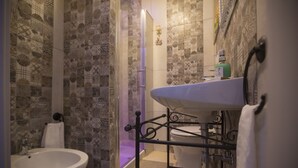 Un baño con baldosas estampadas, un lavabo blanco y cabina de ducha de vidrio.