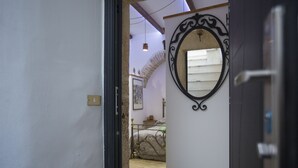 Una puerta que da a un dormitorio con una cama, un espejo decorativo y una mesita.