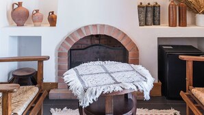 A cozy living room with a brick fireplace, wooden furniture, and decorative vases.