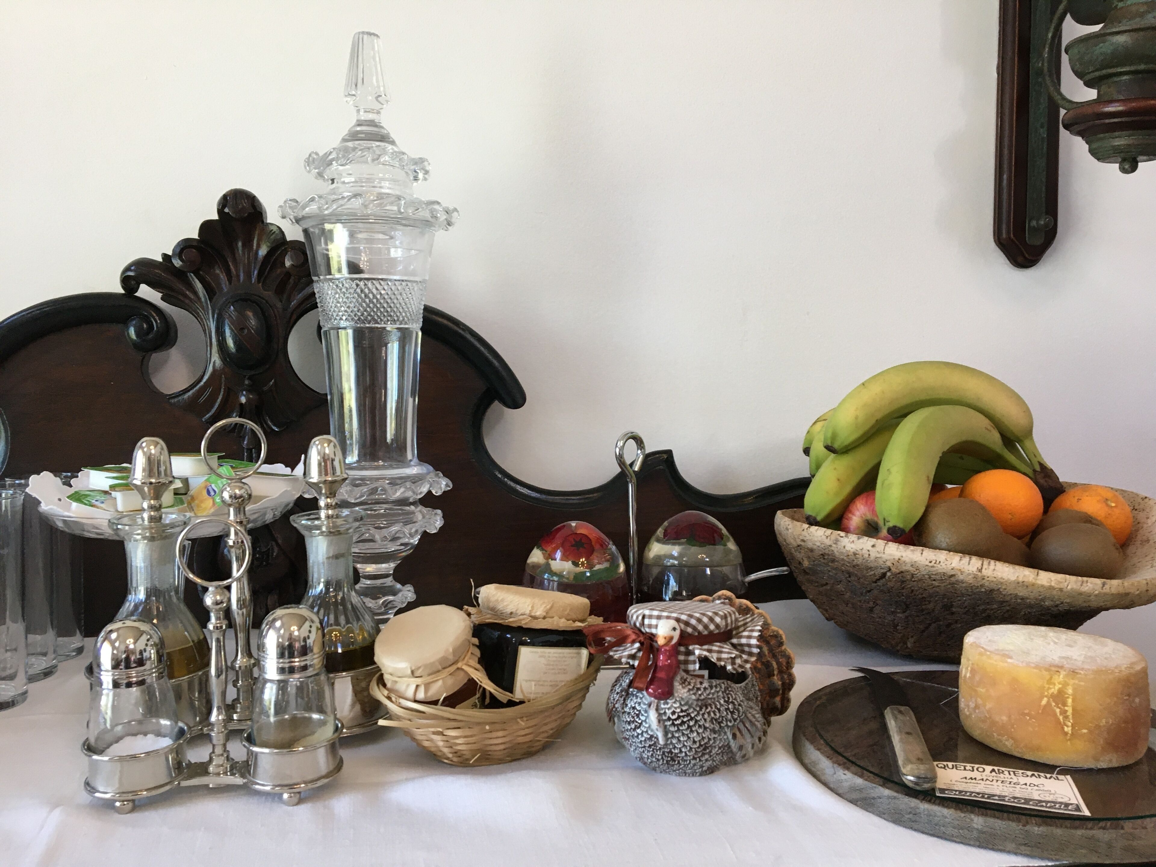 Une table sur laquelle se trouvent divers objets de cuisine, notamment une carafe en verre, des salières et des poivrières, un panier à fruits et une assiette à fromage.