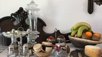 Une table sur laquelle se trouvent divers objets de cuisine, notamment une carafe en verre, des salières et des poivrières, un panier à fruits et une assiette à fromage.