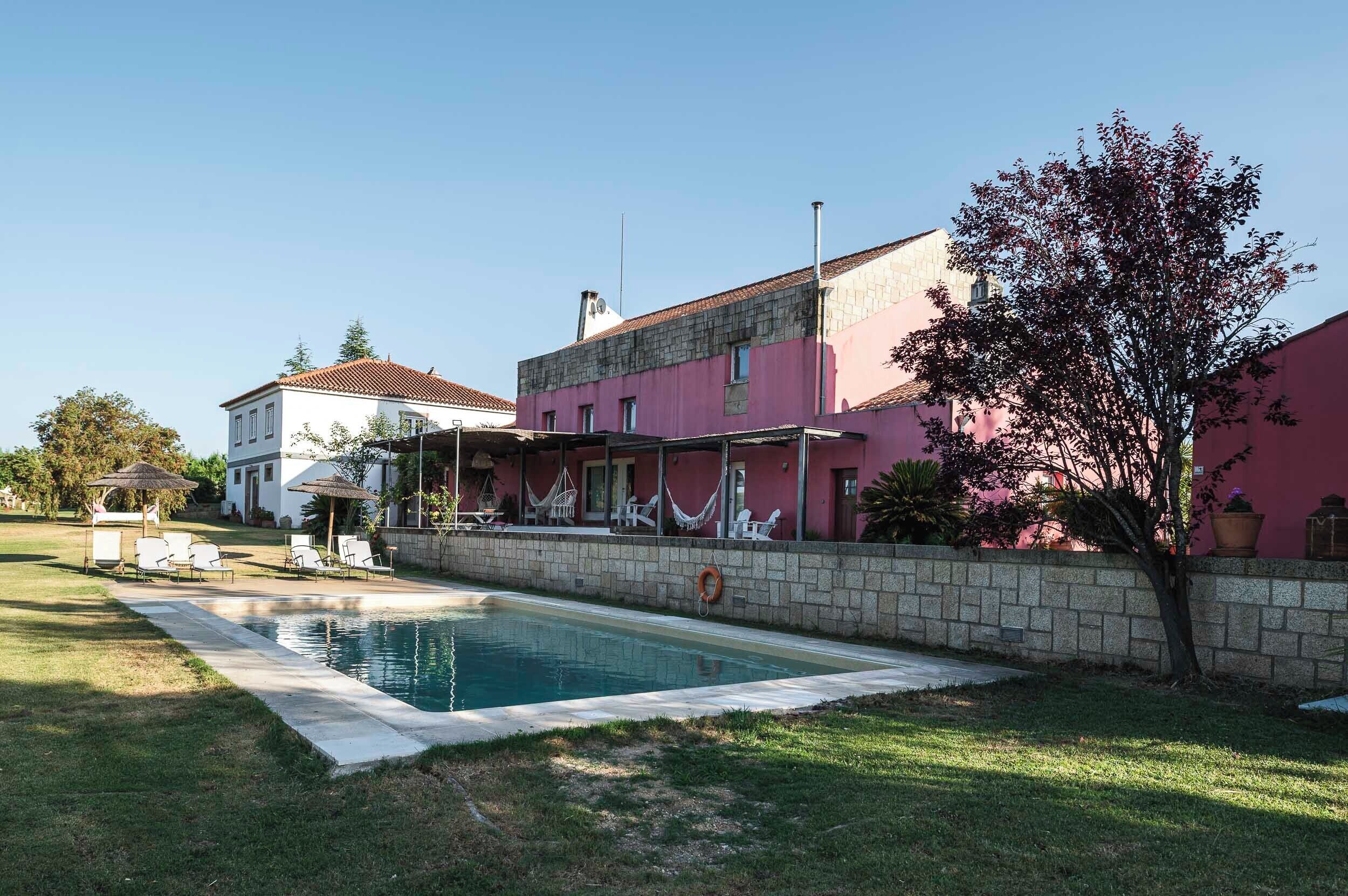 Une maison à deux étages avec une piscine, un espace salon extérieur et un jardin.