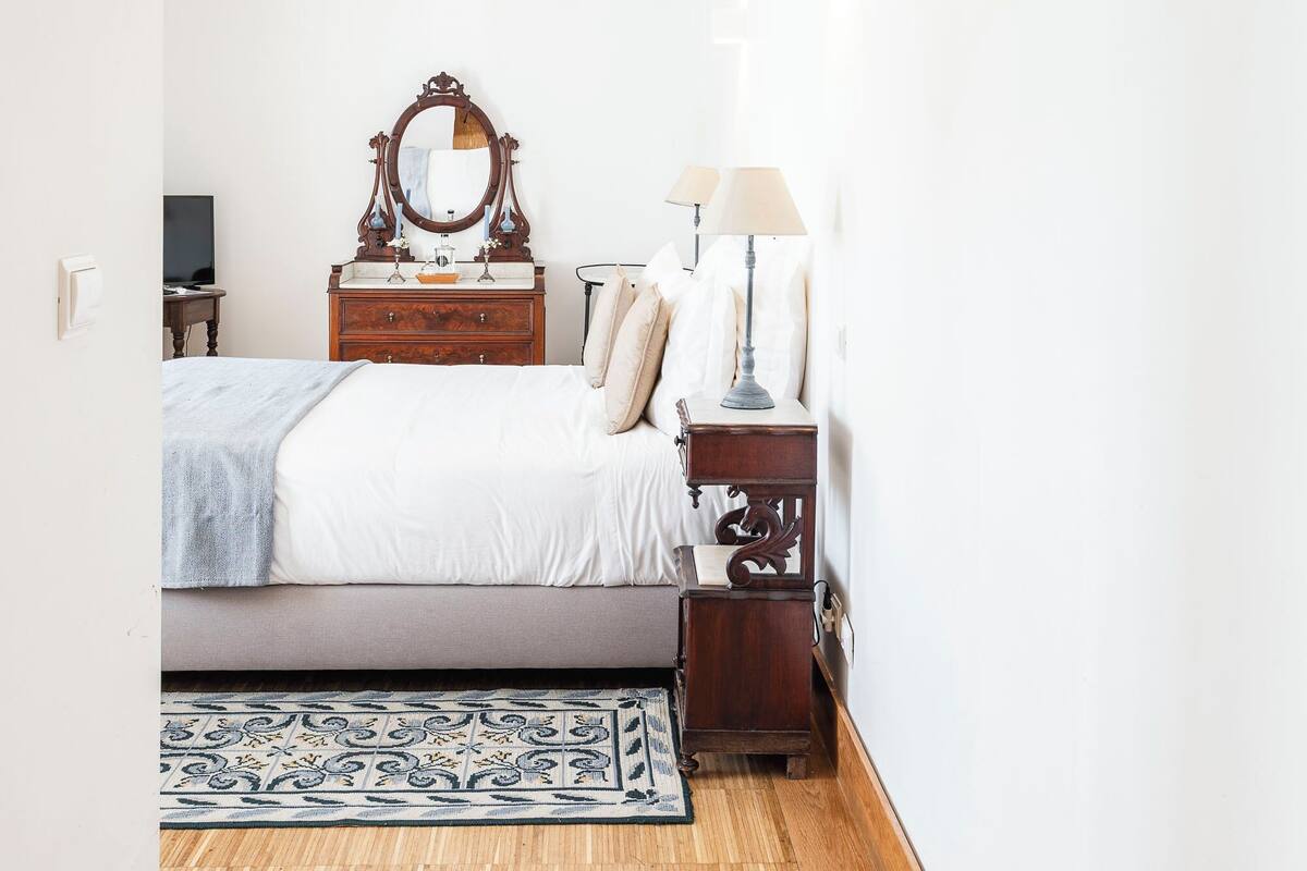 Une chambre à coucher comprenant un lit, une commode, une table de chevet et un miroir.