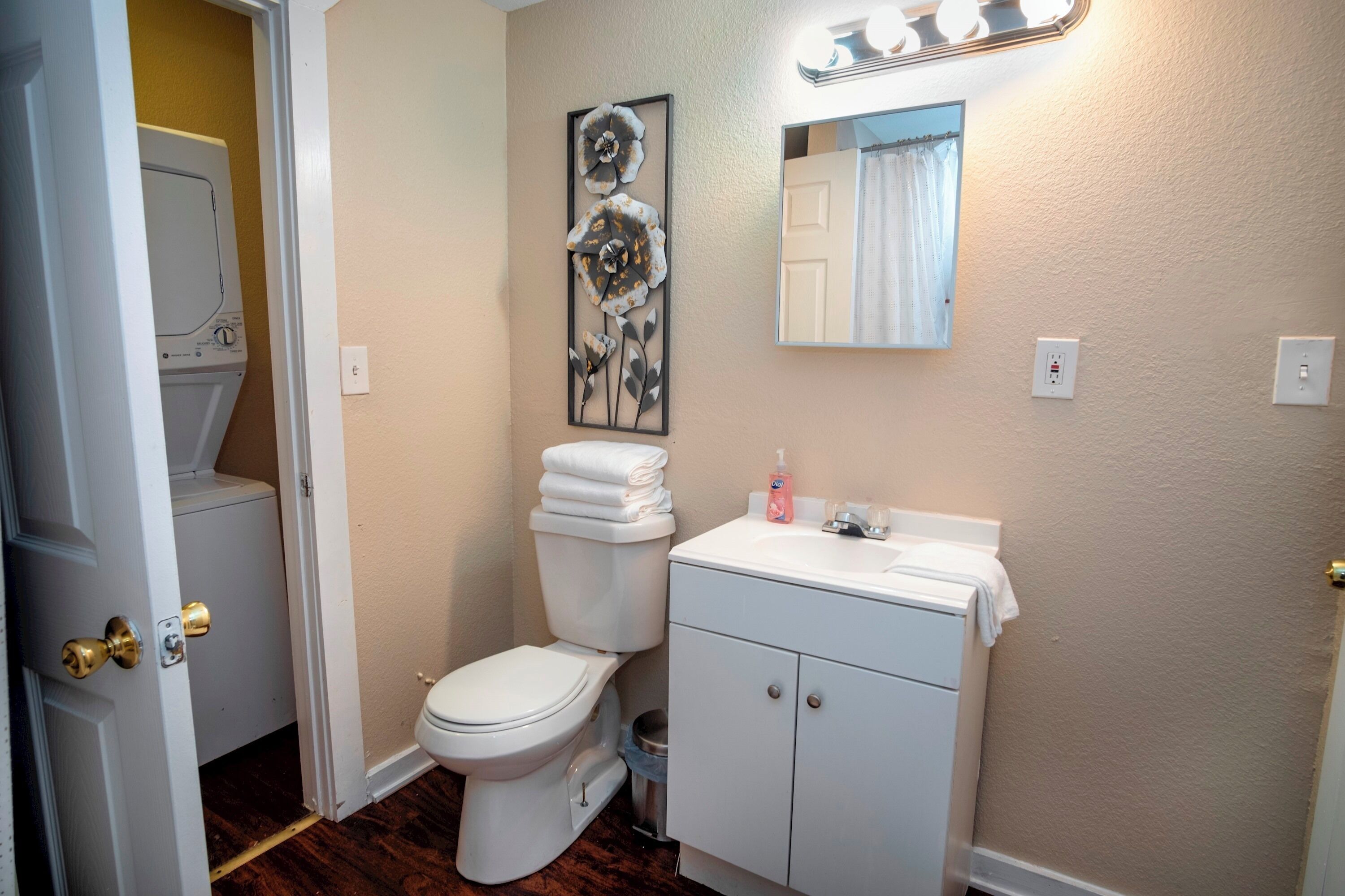 A bathroom with a toilet, sink, and a wall-mounted mirror.