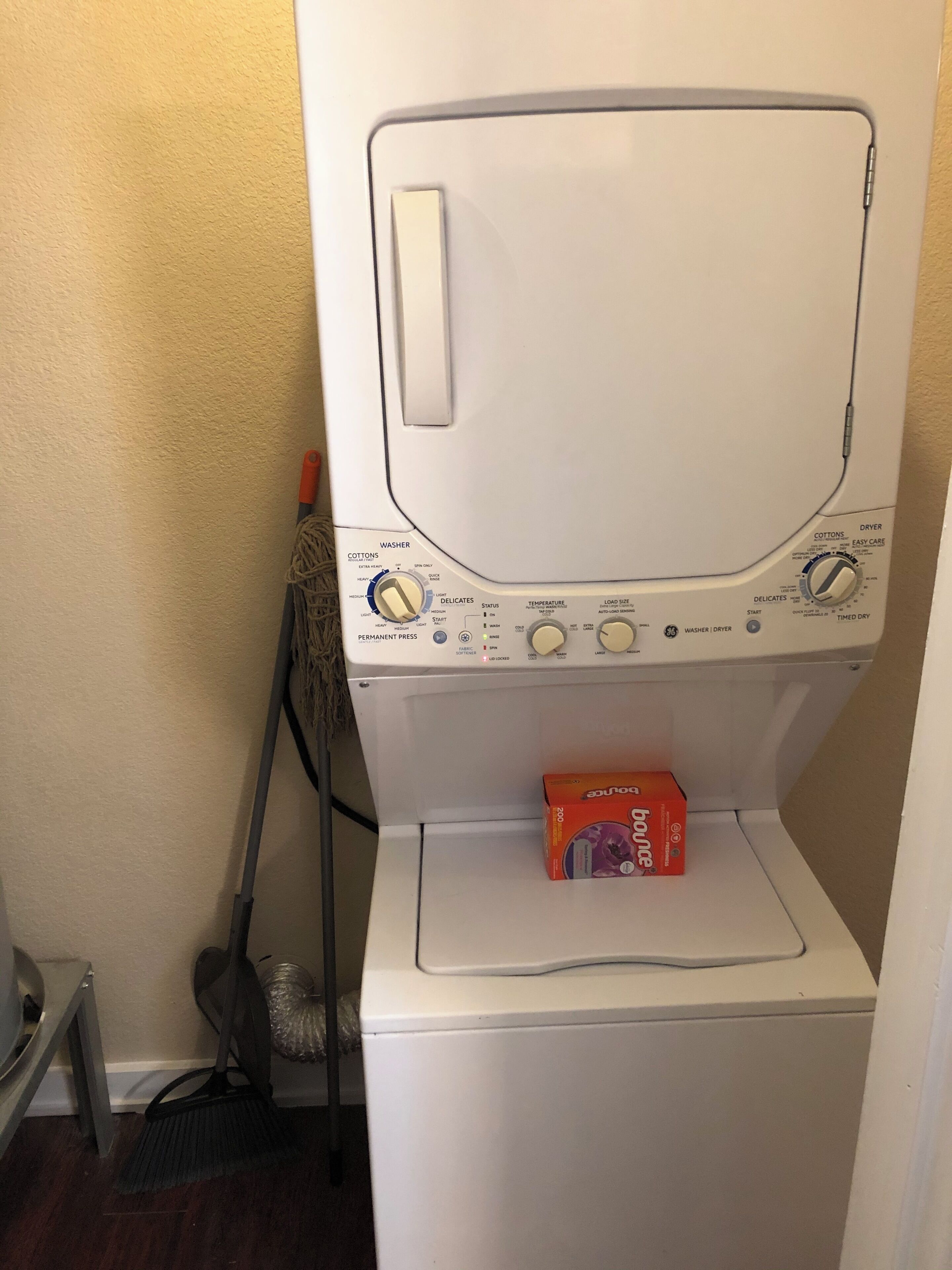 Eine Waschmaschine mit Frontlader, ein Bedienfeld, ein Mop und eine Box mit Bounce Waschmittel auf der Oberseite.