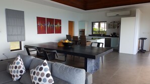 A modern living room with a dining area, a kitchen, and a view of the outdoors.