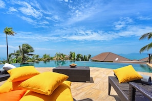 A poolside area with lounge chairs and yellow cushions, overlooking a clear blue sky and a pool. - 1 Bedroom Sea View Villa Bubbles (Koh Samui)