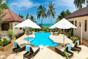 A pool area with lounge chairs and umbrellas, surrounded by palm trees and a view of the ocean. - 5 Bedroom Beachfront Villa Sea Breeze SDV229A-By Samui Dream Villas (Koh Samui)