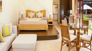 Une chambre à coucher comprenant un lit, des tables de chevet, une table en verre avec des chaises, un canapé et une fenêtre avec des rideaux.