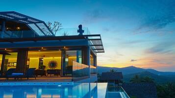 Una casa moderna con fachada de vidrio, piscina y vistas a montañas al atardecer.