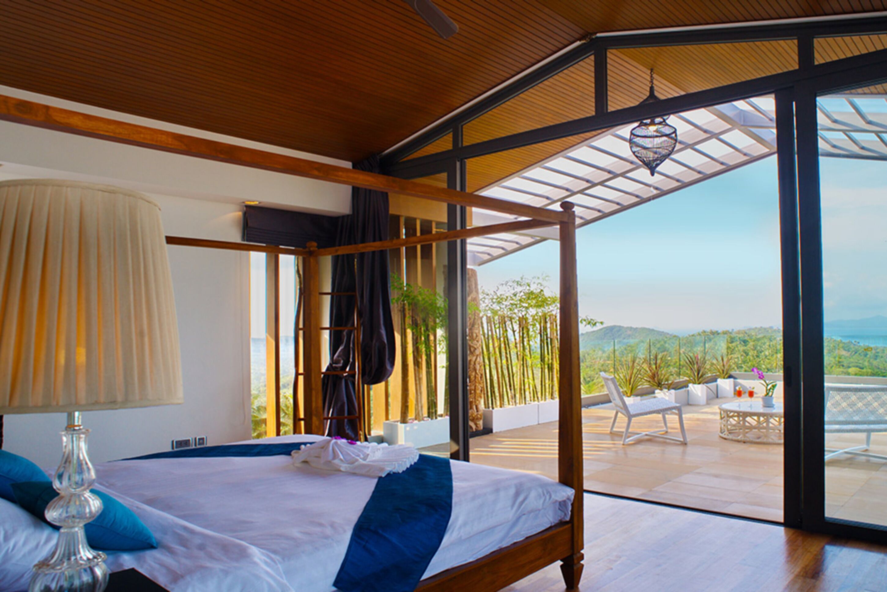 Une chambre moderne avec un grand lit, un ventilateur de plafond et une vue sur l’extérieur.