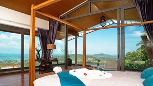 Une chambre spacieuse avec un grand lit, une vue sur l’océan et une structure de plafond en bois.