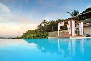 Relax by the serene pool surrounded by lush greenery and palm trees.