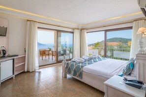 A hotel room with a bed, a desk, a chair, and a balcony with a view.